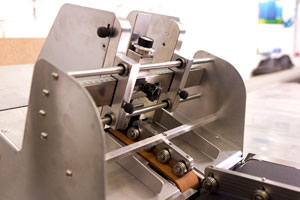 Flexible feeding mechanism of folded packs to the serialization station conveyor
